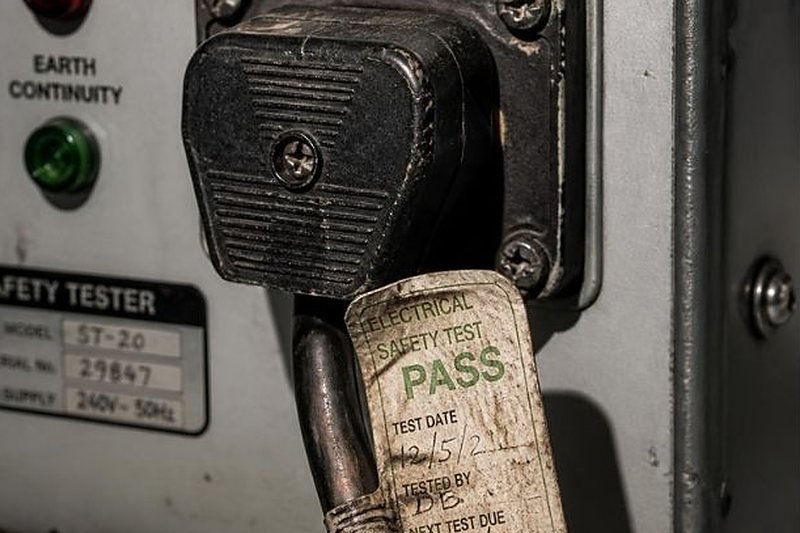 Appliance plug under test with a pass label on the lead